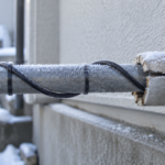 霜が付いた屋外の水道管に凍結防止用ヒーターが巻かれている様子