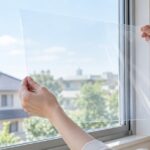 窓ガラスに透明なフィルムを合わせている様子